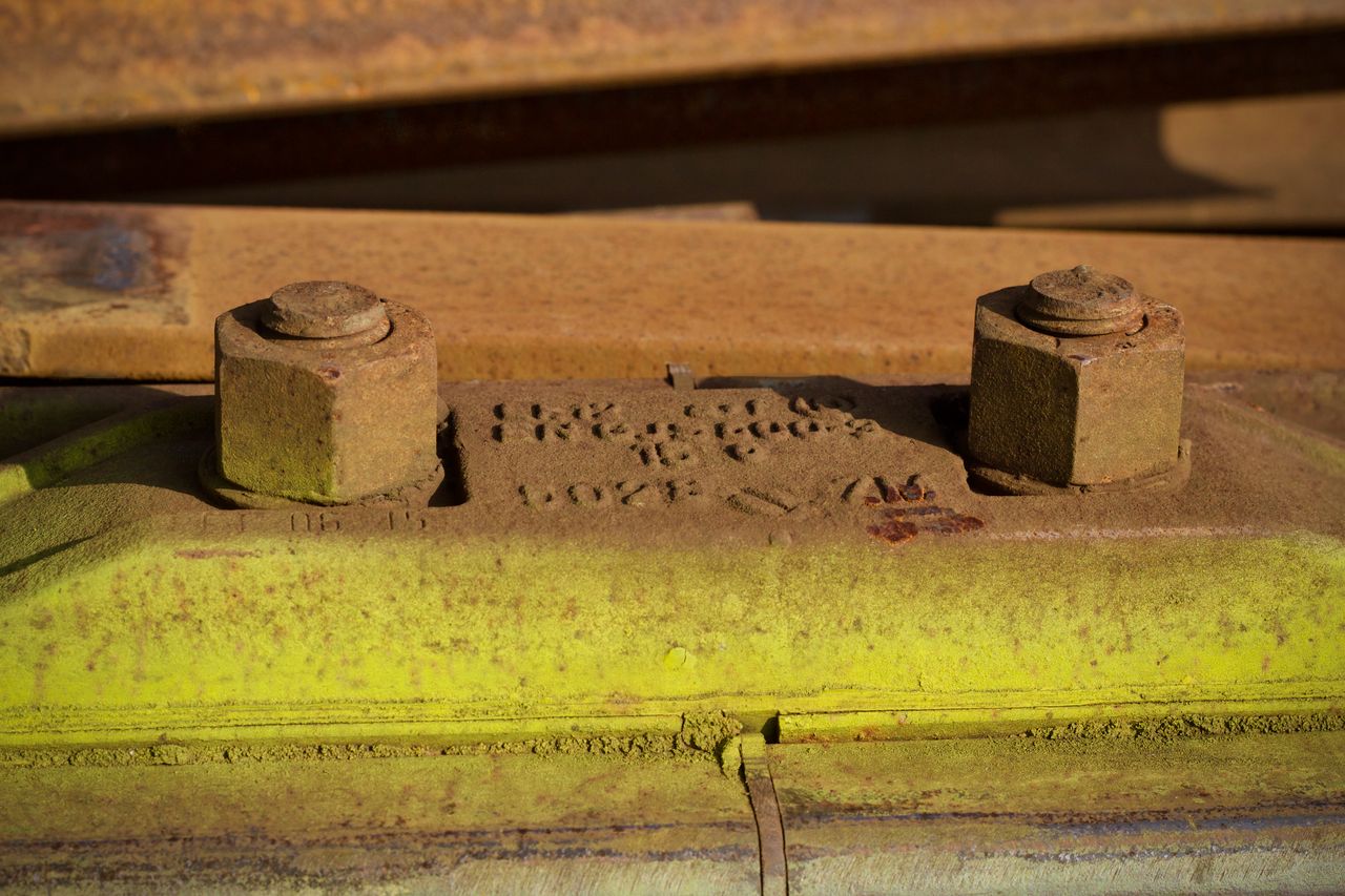 Detailed view of rusty bolts on industrial machinery with a worn and aged appearance, showcasing textures.